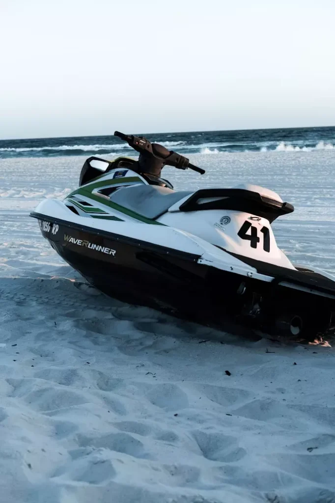 Jet ski WaveRunner blanco y negro en la arena de la playa con el mar al fondo.